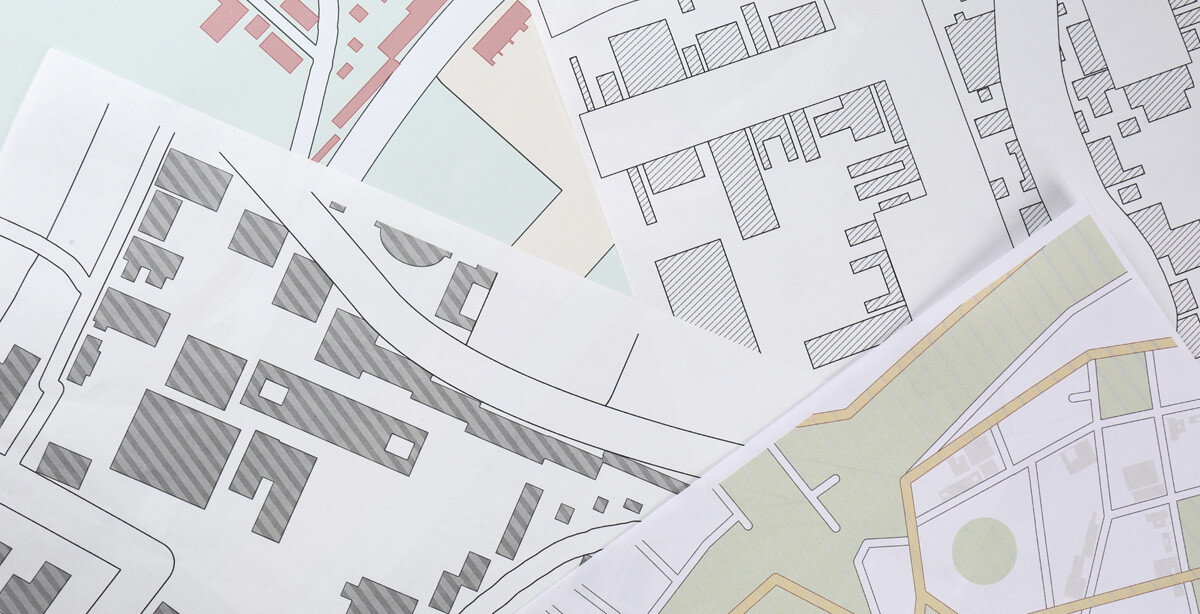 Overhead view of multiple paper maps spread out, showcasing different city layouts and street patterns.
